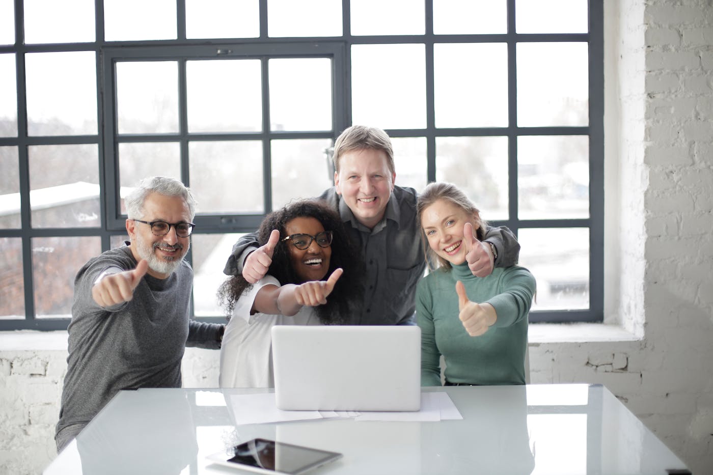 A smiling professional team gathered around a laptop in an office