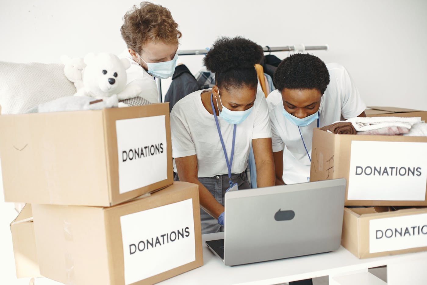 Volunteers organizing donations and reviewing information on a laptop