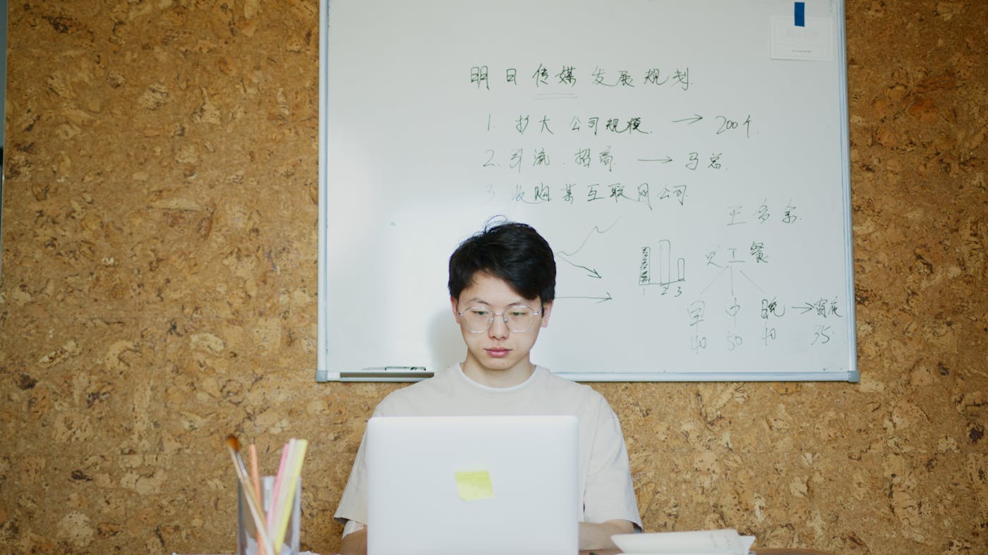 Founder working on a laptop in front of a planning whiteboard